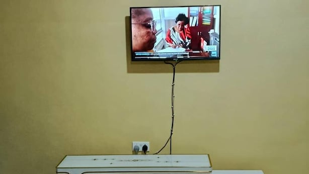 Ein an der Wand befestigter Fernseher mit einem weißen Unterbau darunter.