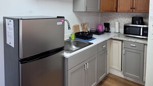 Eine Küche mit Edelstahlkühlschrank, Holzschränken, einer Mikrowelle und einem Geschirrspüler.