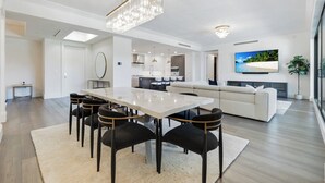 Un salon moderne comprenant un coin repas, une cuisine et un grand écran de télévision.
