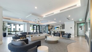 Un hall d’entrée spacieux, doté d’un coin salon, d’un téléviseur et offrant une vue sur l’extérieur.