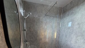 A modern bathroom with a white sink, a large mirror, and a glass-enclosed shower area. - Cabin View (Turriff)