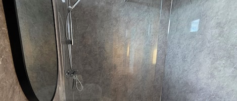 A modern bathroom with a white sink, a large mirror, and a glass-enclosed shower area.
