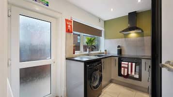 A compact kitchen with a washing machine, a stove, and a microwave.