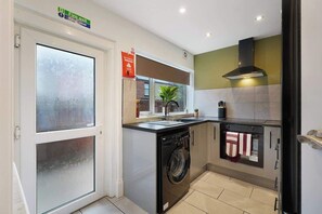 A compact kitchen with a washing machine, a stove, and a microwave.