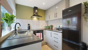 A modern kitchen with a built-in island, stainless steel appliances, and a window with a view. - Modern 4BR with Easy Access to Town and Station (Darlington)