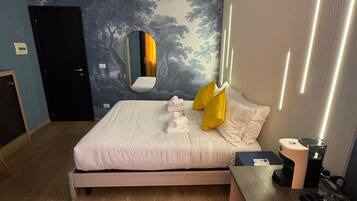 A modern hotel room with a bed, a desk, a mirror, and a wall with a tree mural.