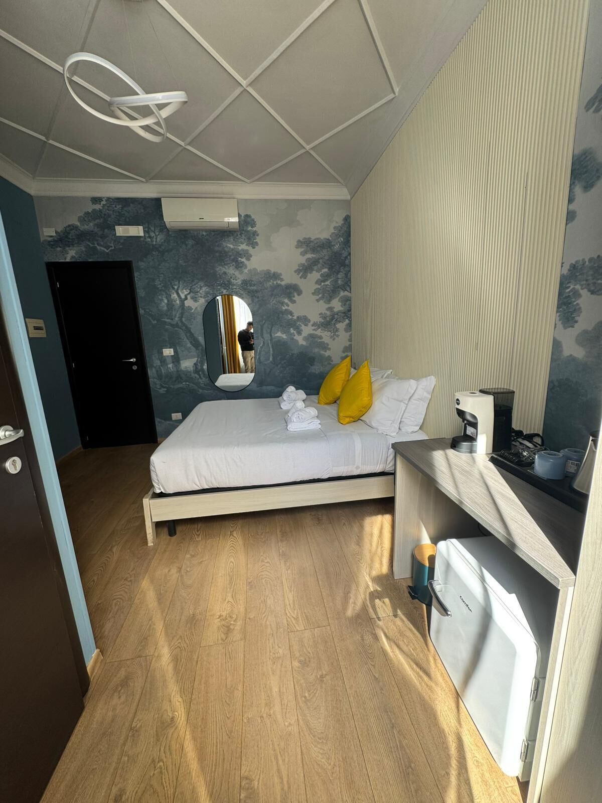 Ett hotellrum med en säng, en spegel, ett skrivbord och en garderob.