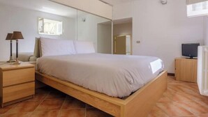 Ein Schlafzimmer mit Bett, Nachttisch, Lampe, Fernseher und Spiegel.