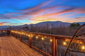 A wooden deck with a railing, string lights, and a view of mountains. - LeConte Views - Hot Tub - Game Loft - Remodeled (Gatlinburg)