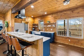 A wooden interior with a bar area, kitchen, and large windows. - LeConte Views - Hot Tub - Game Loft - Remodeled (Gatlinburg)