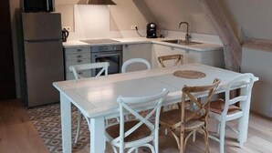 A compact kitchen with a white table and chairs, a microwave, a coffee maker, and a sink. - La Petite Histoire (Ath)