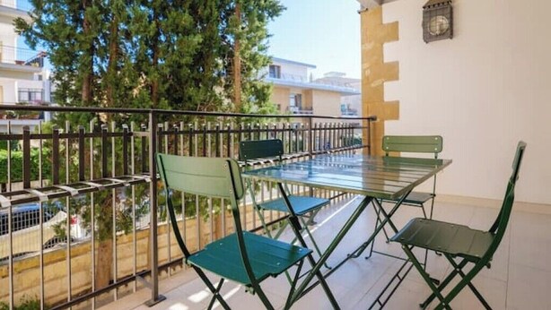 A balcony with a table and chairs, a railing, and a view of buildings and trees. - Cozy apartment in Lecce, parking (Lecce)