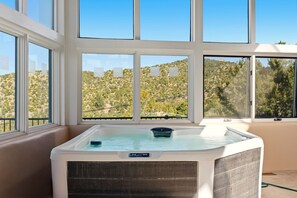 A hot tub in a room with large windows overlooking a hilly landscape. - New Listing! The Grand Overlook | Pool + Hot Tubs | Long-Range Views (Santa Fe)