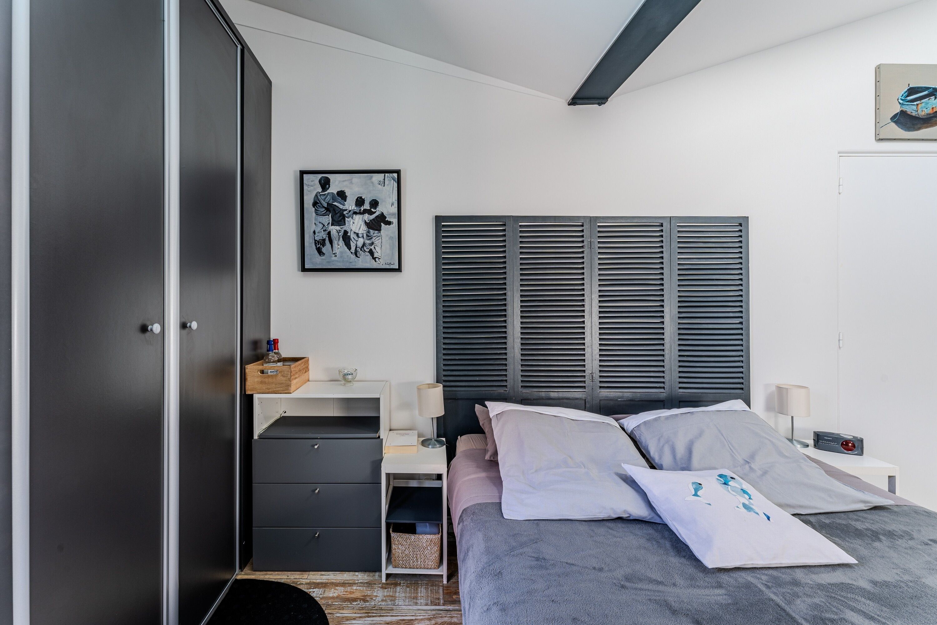 Une chambre à coucher comprenant un lit, des tables de chevet, une armoire et une œuvre d’art accrochée au mur.