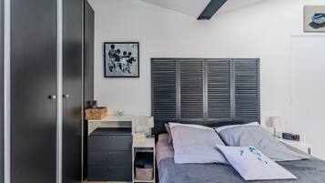 Une chambre à coucher comprenant un lit, des tables de chevet, une armoire et une œuvre d’art accrochée au mur.
