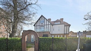 A two-story house with a brick archway entrance, a large window, and a clear sky. - London 2 Bed Premium Flat (London)