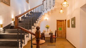 A staircase with a wooden handrail, a dining area with a table and chairs, and a door with a green turtle decoration. - ELIVAAS Amayah Vayu 6 BHK Villa (Assagao)