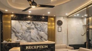 A reception area with a marble counter, a ceiling fan, and a clock on the wall. - Hotel Luxe Stay - Delhi Airport (New Delhi)
