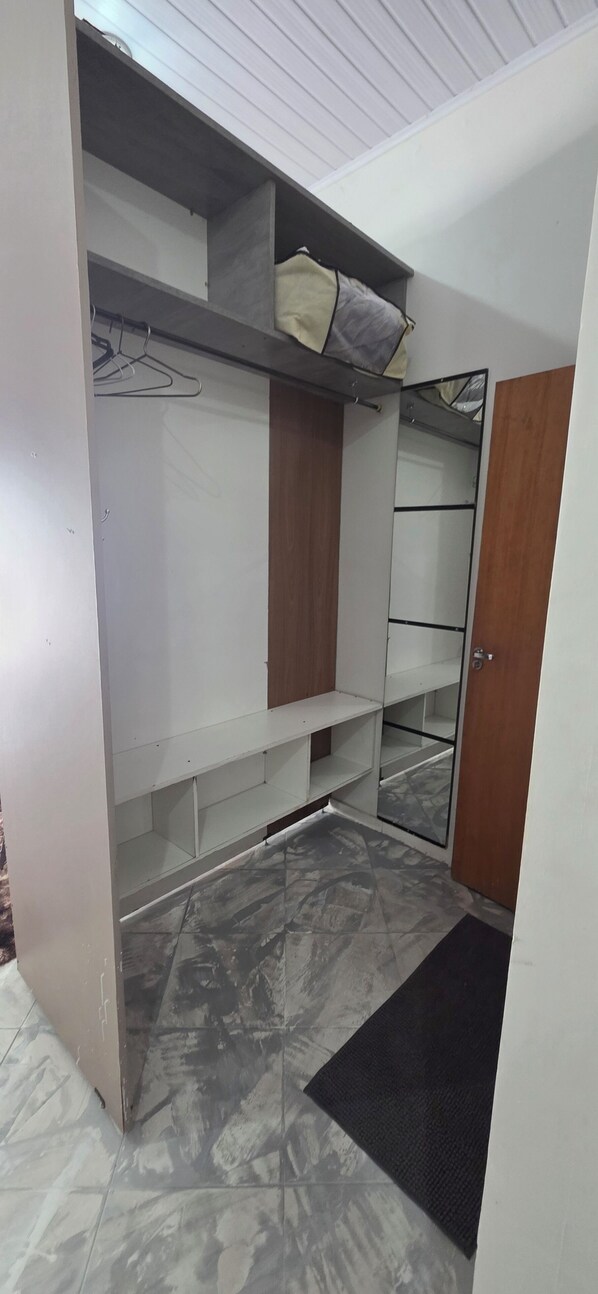 A room with a wardrobe, a mirror, and a tiled floor.