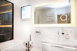 Un baño moderno con un espejo grande, un porta papel higiénico, un lavabo y un perchero para toallas.