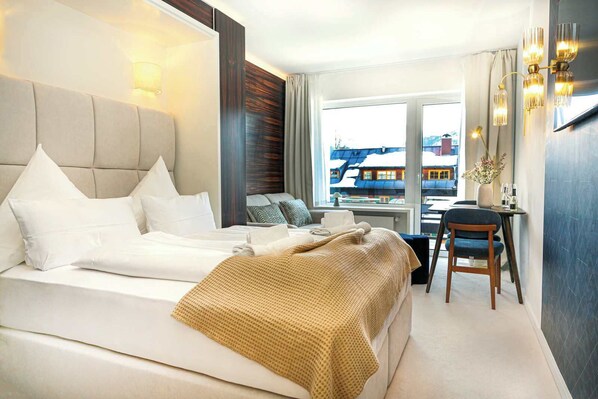 Una habitación de hotel con una cama, un escritorio, una silla y vistas a edificios.