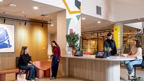 A reception area with a counter, seating, and a staircase. - Student only Ensuite Stapleton House (London)