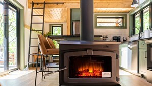 A modern kitchen with a wood-burning stove, a ladder, and a view of the outdoors. - Secluded Cabin with King Bed and Fire Pit on 48 Private Acres (Carroll County)