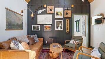 A cozy room with a brown leather sofa, a green armchair, a small wooden table, and a patterned rug.