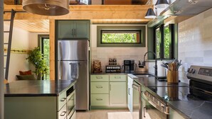 A modern kitchen with a stainless steel refrigerator, a coffee maker, and a window. - Secluded Cabin with King Bed and Fire Pit on 48 Private Acres (Carroll County)