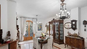 Un espace repas comprenant une table, des chaises, un lustre, un buffet et un miroir.