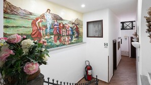 Un couloir orné d’une fresque murale, muni d’un extincteur et d’un escalier.