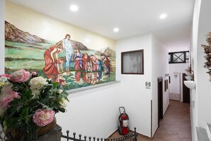 A hallway with a mural, a fire extinguisher, and a staircase. - Villa Pompeii Ruiins with Private Terrace, Wi-Fi, and Air Conditioning (Torre Annunziata)