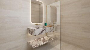 Une salle de bain dotée d’un meuble-lavabo en marbre, d’un grand miroir et d’une cabine de douche en verre.