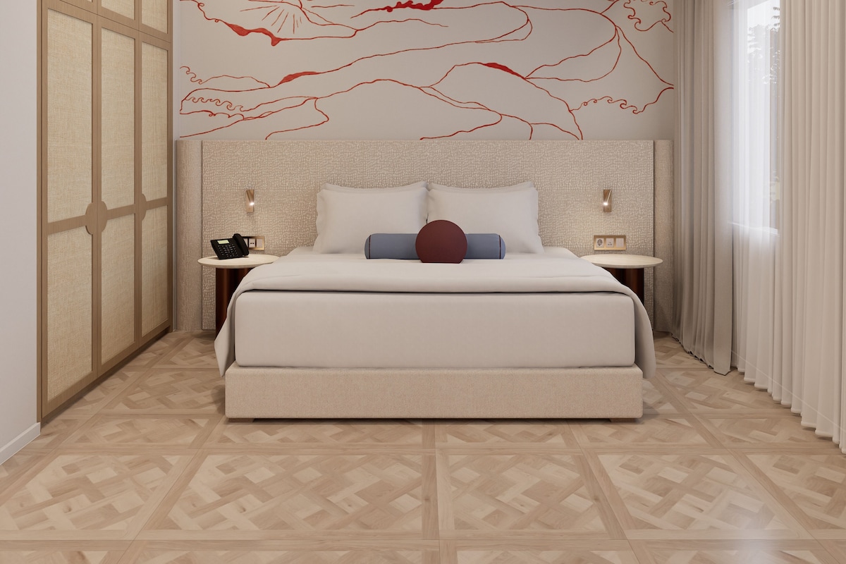Ein modernes Hotelzimmer mit einem großen Bett, einem Nachttisch, einem an der Wand montierten Telefon und einem dekorativen Wandbild.