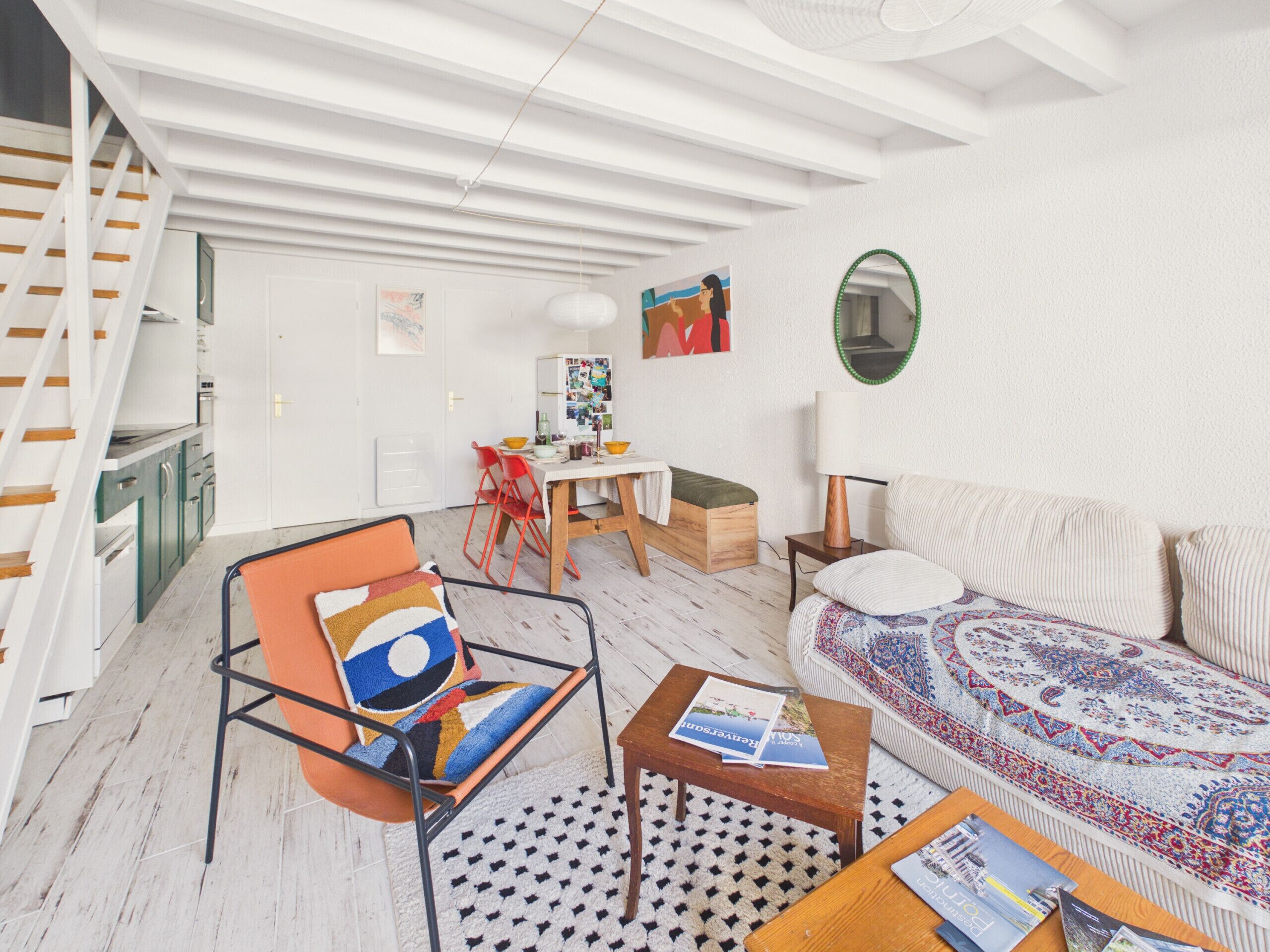 Ein modernes Wohnzimmer mit einer Couch, einem Sessel, einem Tisch und einer Treppe.