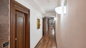 Un corridoio con pavimento in legno, una porta con la scritta '2' e un punto luce fissato al muro.