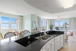 Una cocina moderna con una isla grande, un comedor con sillas y vista al océano.