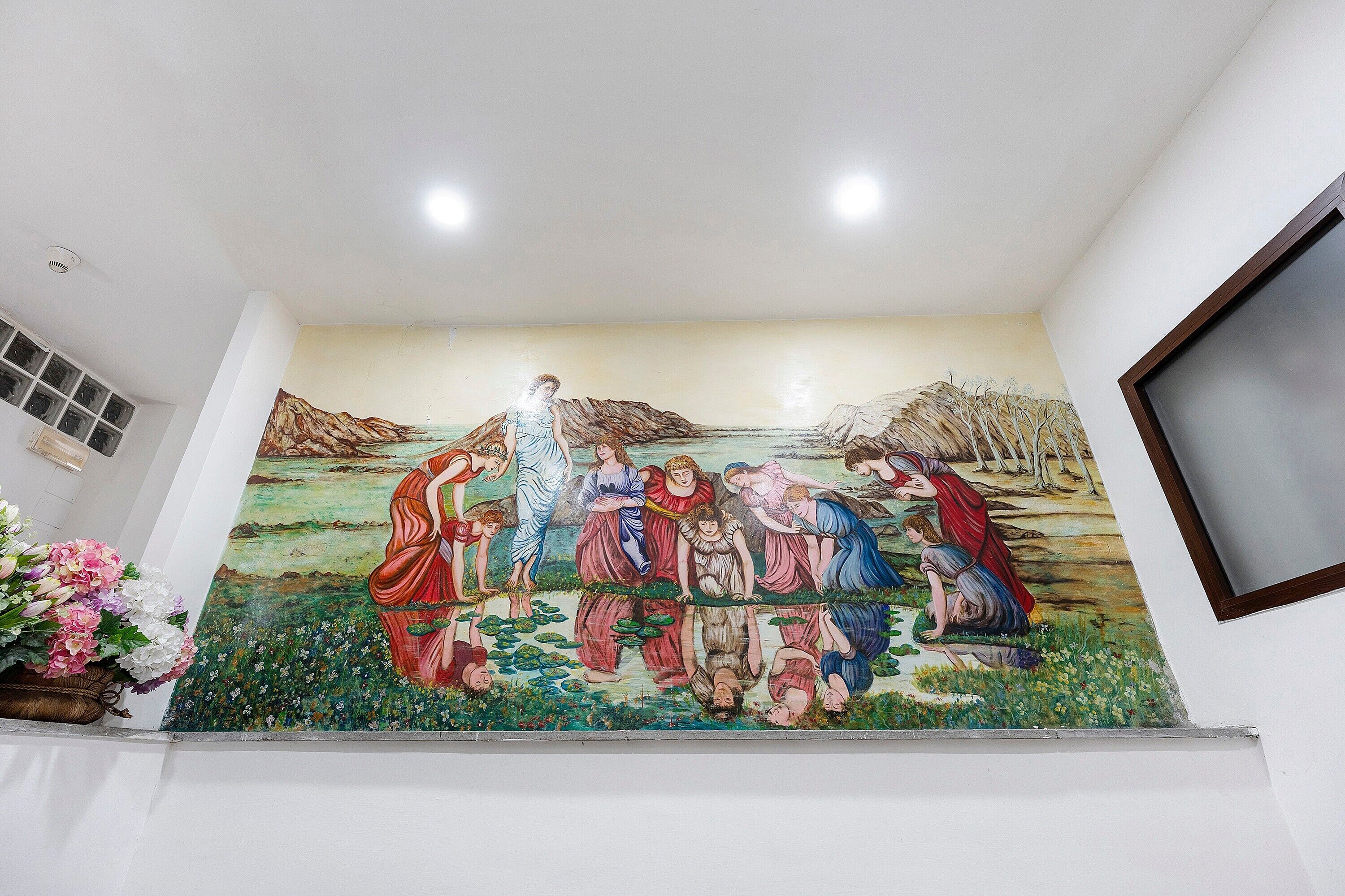 Un murale raffigura figure con abiti svolazzanti, una finestra con persiane e una pianta in vaso.
