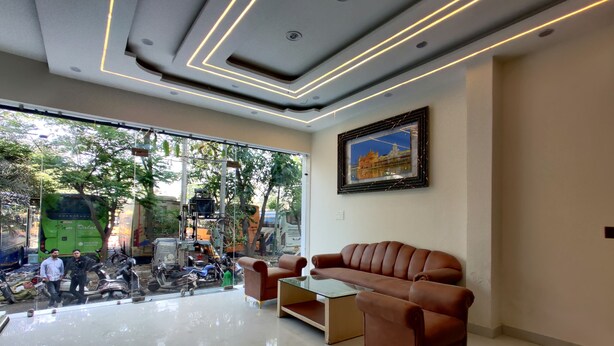 A modern interior with a sofa, a framed picture, and a view of the street outside. - Hotel Kalra (Amritsar)
