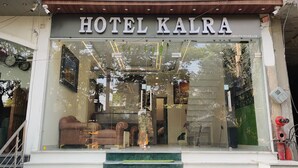A hotel entrance with a sign reading 'HOTEL KALRA,' a staircase leading up, and a glimpse of interior furnishings. - Hotel Kalra (Amritsar)