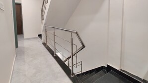 A modern staircase with a metal handrail, white walls, and a marble floor. - Hotel Kalra (Amritsar)