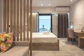 Une chambre d’hôtel équipée d’un lit, d’un bureau, d’une chaise et offrant une vue sur la mer grâce à une grande fenêtre.