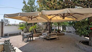 Eine Außenpatio mit Steinboden, zwei Holzbanken und einem Tisch mit Stühlen.