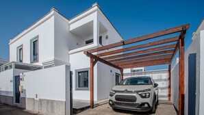 Un edificio moderno de dos pisos con un coche estacionado en la entrada.