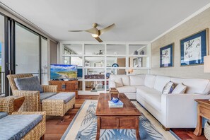 Ein modernes Wohnzimmer mit einem weißen Sofa, Korbmöbeln, einem Holztisch und einem Deckenventilator.
