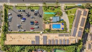 An aerial view of a hotel with a swimming pool, parking lot, and solar panels. - Maui Parkshore #415 Ocean View in the Heart of Kihei, Walk to Kamaole Beach (Kihei)