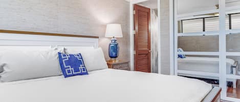 Habitación de hotel con una cama grande, una mesita de noche con lámpara, una puerta de madera y vistas a un balcón.