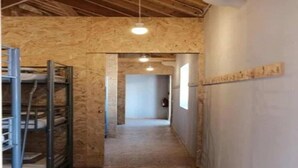 Een hal met open houten wanden, een metalen trap en een plafond met zichtbare balken.