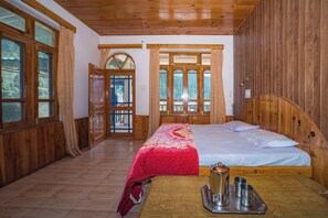 A wooden room with a bed, a table with a tray, and a view through a door. - Forest Rest House Barot (Barot)