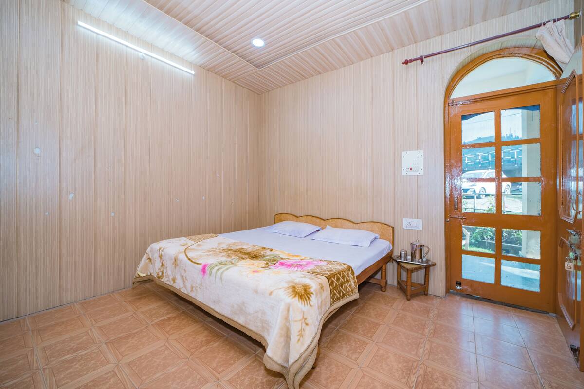 A bedroom with a bed, a wooden door, and a tiled floor.